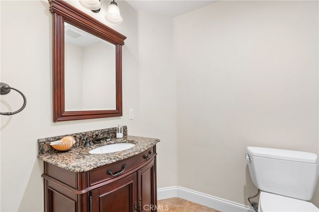 a bathroom with a granite countertop sink and a toilet