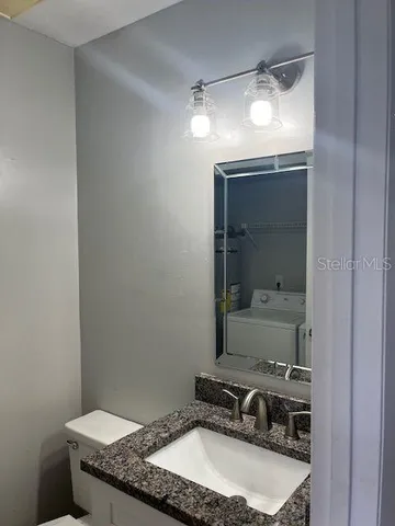 a bathroom with a granite countertop sink and a toilet