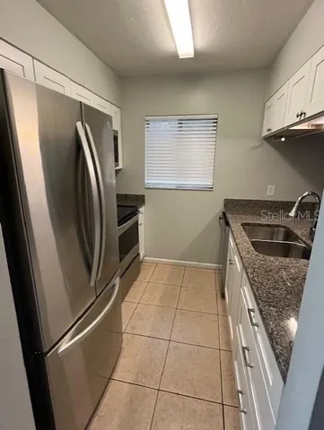 a kitchen with stainless steel appliances granite countertop a refrigerator a sink and a stove