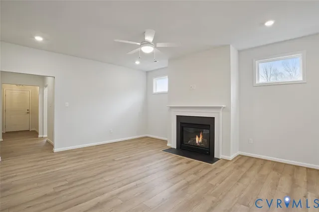 an empty room with wooden floor fireplace and window