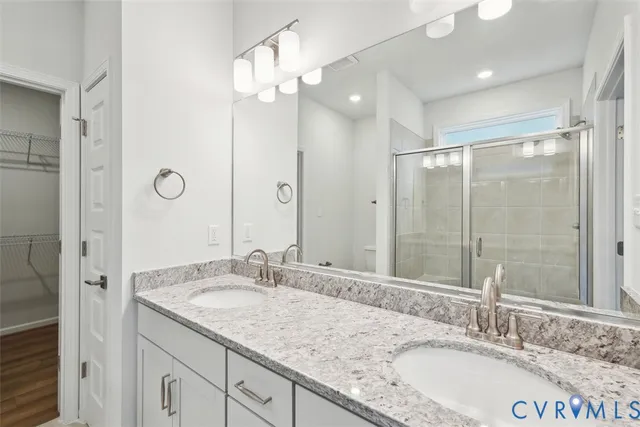 a bathroom with a granite countertop sink double mirror and shower