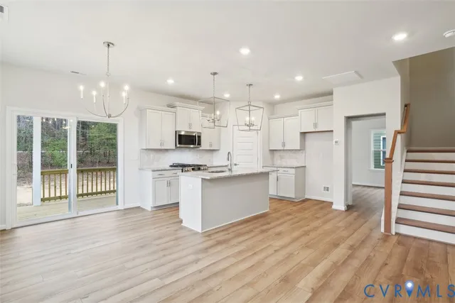 a large kitchen with granite countertop a large counter top a sink stainless steel appliances and cabinets