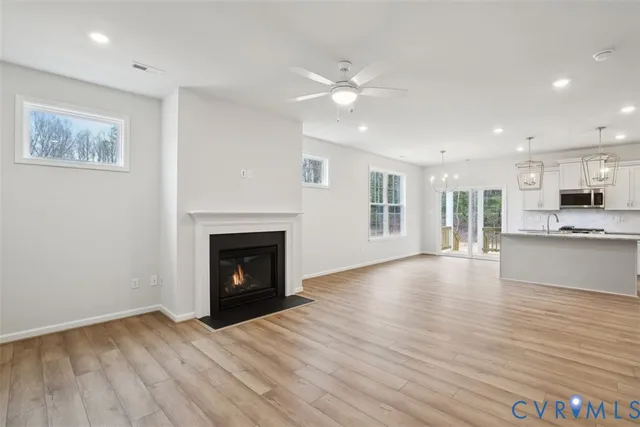 a view of an empty room with wooden floor and a fireplace