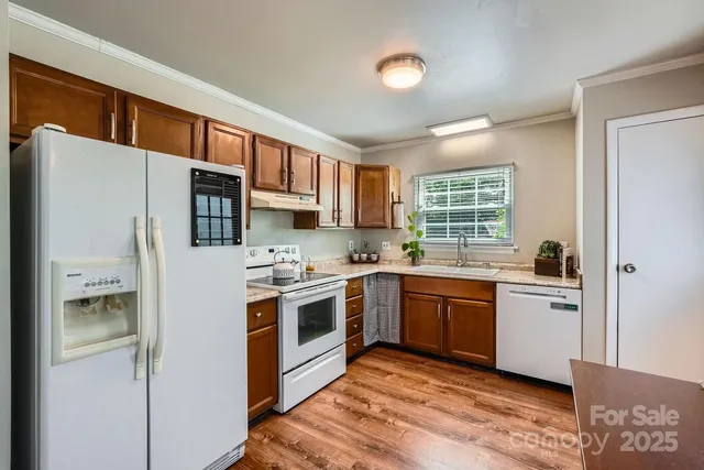 a kitchen with stainless steel appliances granite countertop a refrigerator a stove top oven a sink and dishwasher with wooden floor