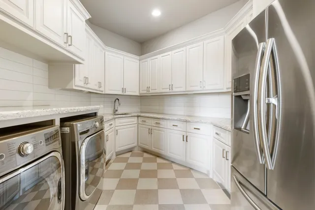 a kitchen with stainless steel appliances granite countertop a refrigerator sink and white cabinets