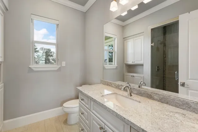 a bathroom with a granite countertop toilet a sink and mirror