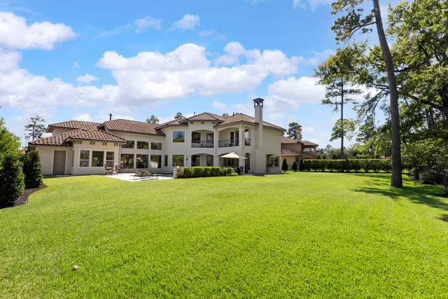 a view of a big house with a big yard and large trees