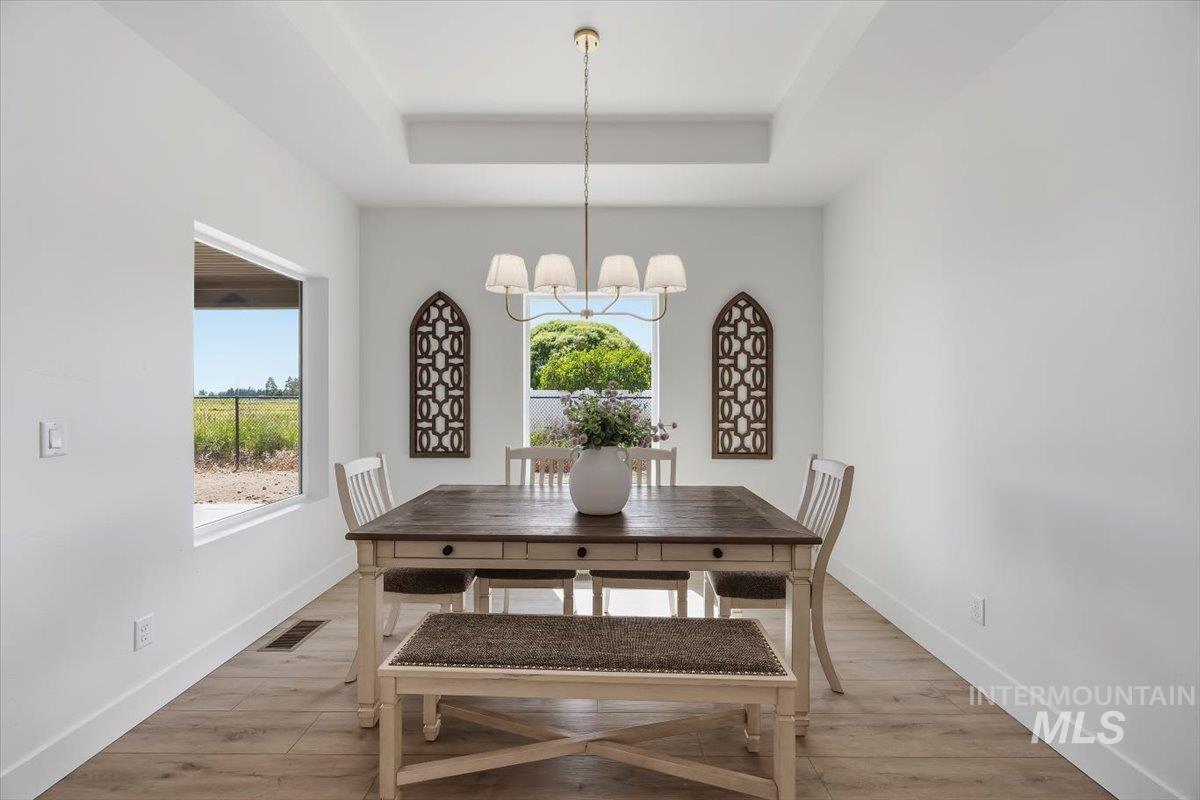 2005 Sparrow Street Rupert, ID 83350 - Photo 14 of 30 Bright dining area featuring a tray ceiling, wood-finish flooring, and ample natural light from multiple windows
