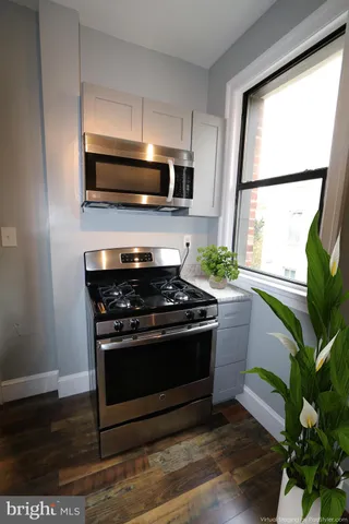 a kitchen with stainless steel appliances a stove a microwave and a potted plant