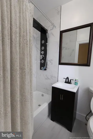 a bathroom with a bathtub sink vanity mirror and toilet