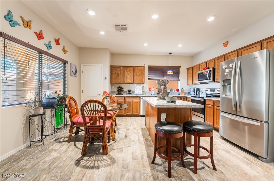 4732 Adriano Way Pahrump, NV 89061 - Photo 15 of 44 Kitchen with appliances with stainless steel finishes, brown cabinetry, recessed lighting, pendant lighting, and light wood-style floors
