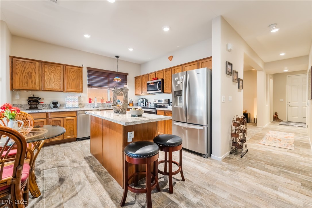 4732 Adriano Way Pahrump, NV 89061 - Photo 16 of 44 Kitchen featuring appliances with stainless steel finishes, brown cabinetry, decorative light fixtures, light wood-type flooring, and recessed lighting