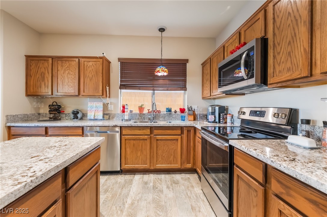 4732 Adriano Way Pahrump, NV 89061 - Photo 18 of 44 Kitchen featuring brown cabinetry, appliances with stainless steel finishes, and pendant lighting