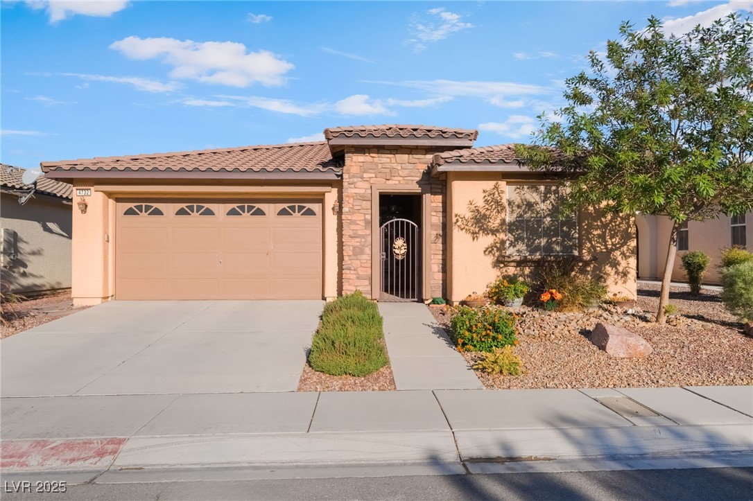 4732 Adriano Way Pahrump, NV 89061 - Photo 2 of 44 Mediterranean / spanish-style house featuring stucco siding, stone siding, concrete driveway, a tile roof, and a garage