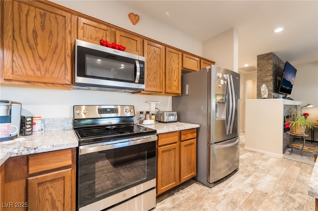 4732 Adriano Way Pahrump, NV 89061 - Photo 21 of 44 Kitchen with appliances with stainless steel finishes, brown cabinets, light stone counters, and recessed lighting