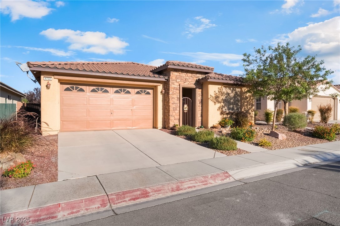 4732 Adriano Way Pahrump, NV 89061 - Photo 3 of 44 Mediterranean / spanish home featuring stone siding, stucco siding, a tiled roof, a garage, and concrete driveway