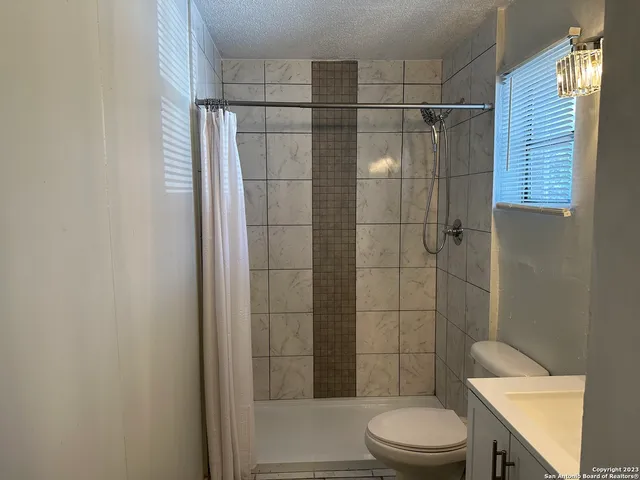 a bathroom with a shower a toilet and sink