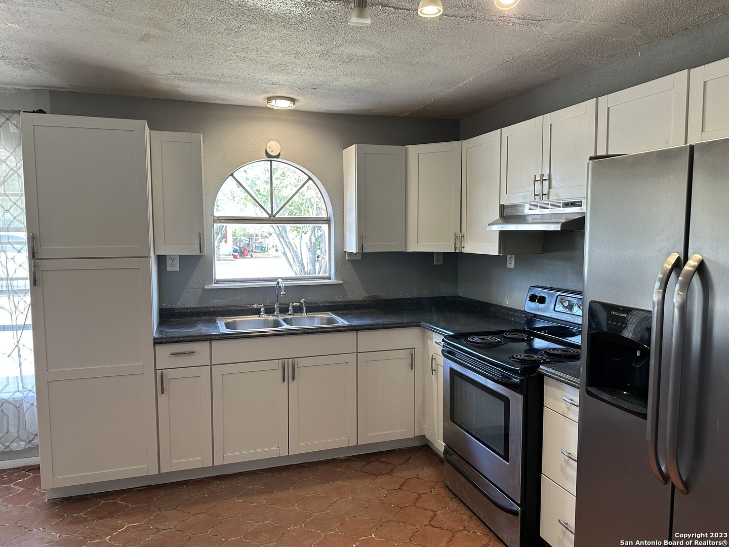 403.5 Retta Street Carrizo Springs, TX 78834 - Photo 9 of 17 a kitchen with stainless steel appliances granite countertop a sink a stove a refrigerator a window and cabinets