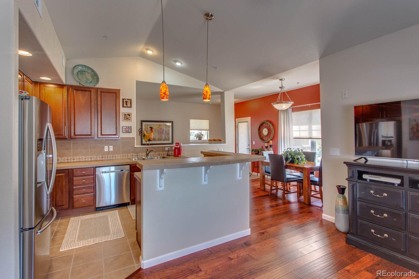 6292 Kilmer Loop, Unit 204 Arvada, CO 80403 - Photo 12 of 25 a kitchen with stainless steel appliances granite countertop a refrigerator a stove top oven a sink dishwasher and wooden cabinets with wooden floor