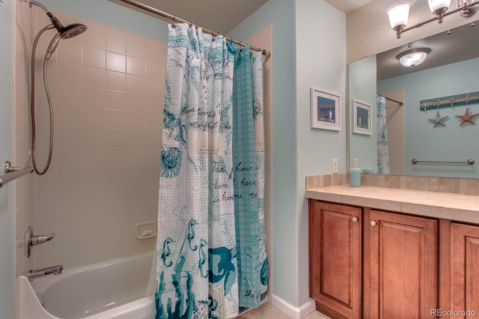 6292 Kilmer Loop, Unit 204 Arvada, CO 80403 - Photo 19 of 25 a bathroom with a granite countertop sink a mirror and a bathtub
