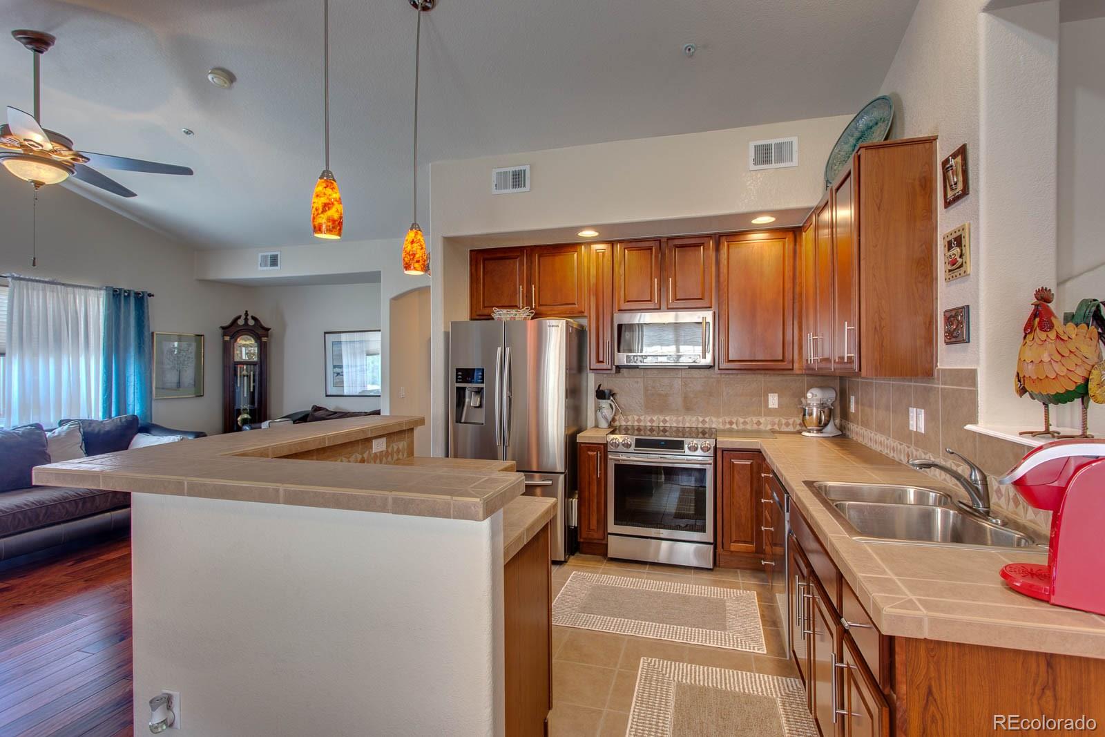 6292 Kilmer Loop, Unit 204 Arvada, CO 80403 - Photo 8 of 25 a kitchen that has a sink stainless steel appliances a counter top space cabinets and a window