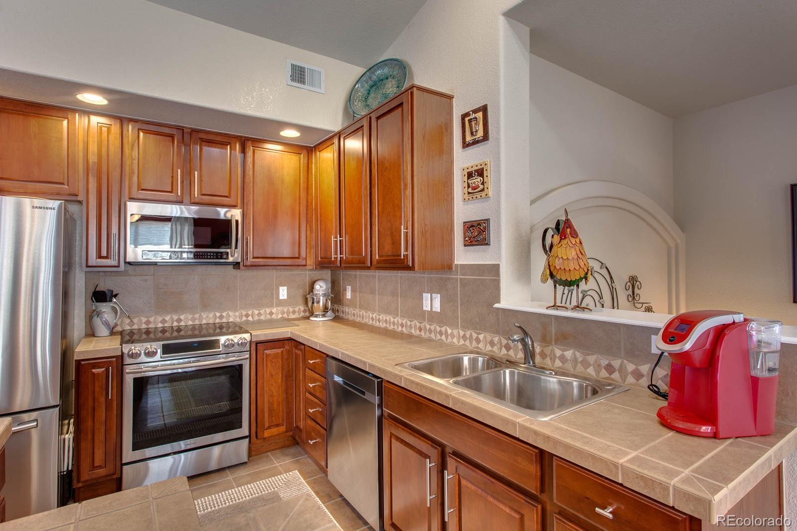 6292 Kilmer Loop, Unit 204 Arvada, CO 80403 - Photo 9 of 25 a kitchen with stainless steel appliances granite countertop a sink and cabinets with wooden floor