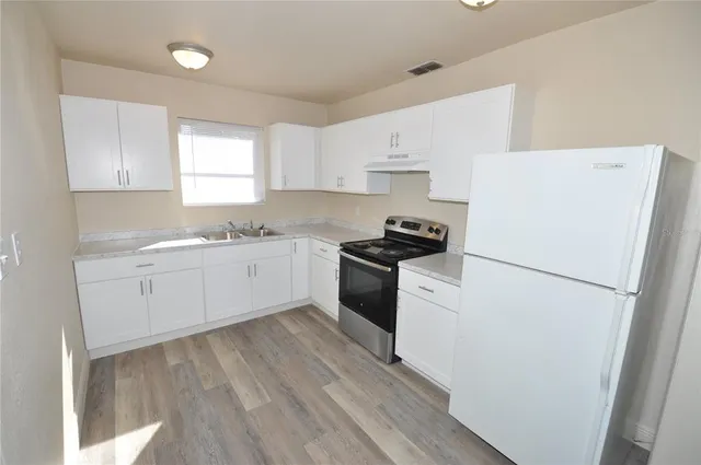 a kitchen with cabinets appliances a sink and a window