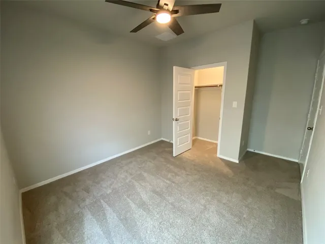 an empty room with a ceiling fan and bathroom view