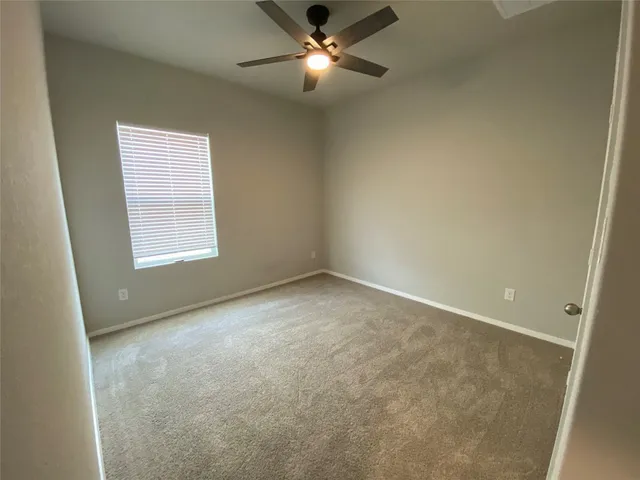 an empty room with a ceiling fan and window