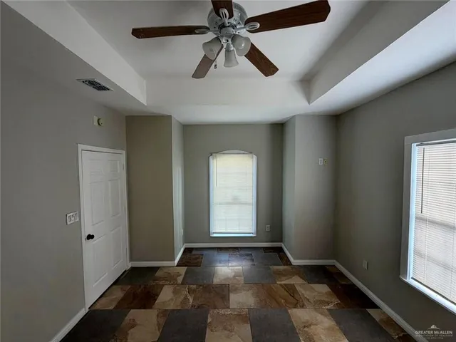 an empty room with windows and fan
