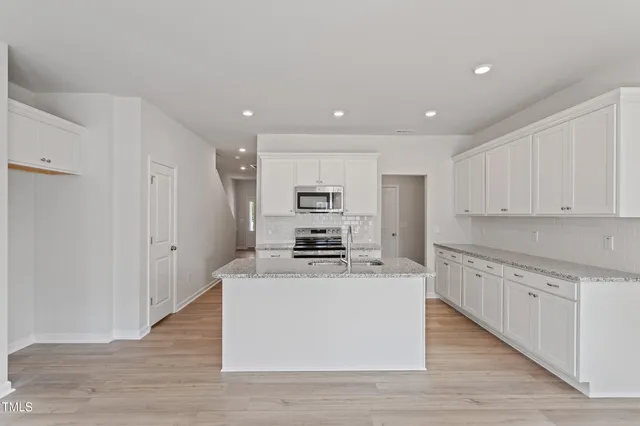 a large kitchen with stainless steel appliances granite countertop a stove a sink dishwasher and a refrigerator with wooden floor