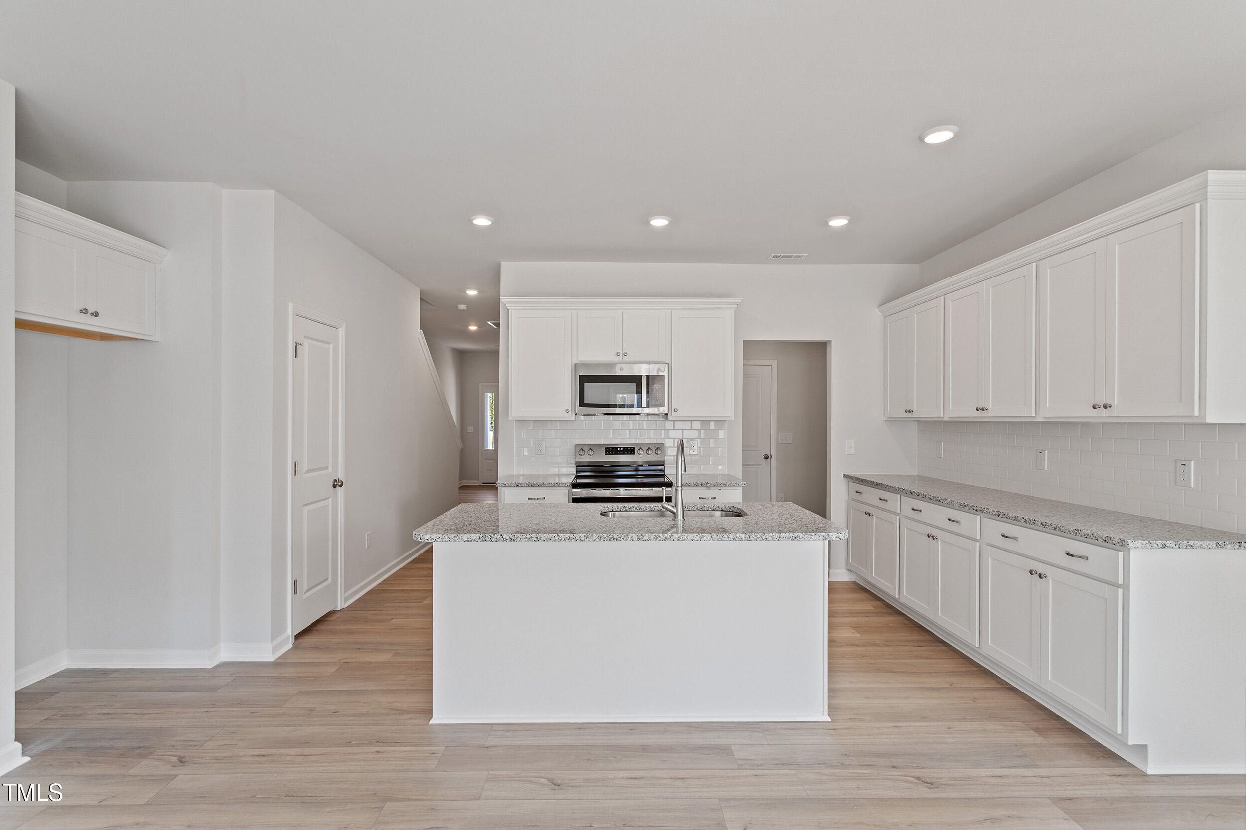 123 Powell Townes Way, Unit 302 Raleigh, NC 27603 - Photo 15 of 44 a large kitchen with stainless steel appliances granite countertop a stove a sink dishwasher and a refrigerator with wooden floor