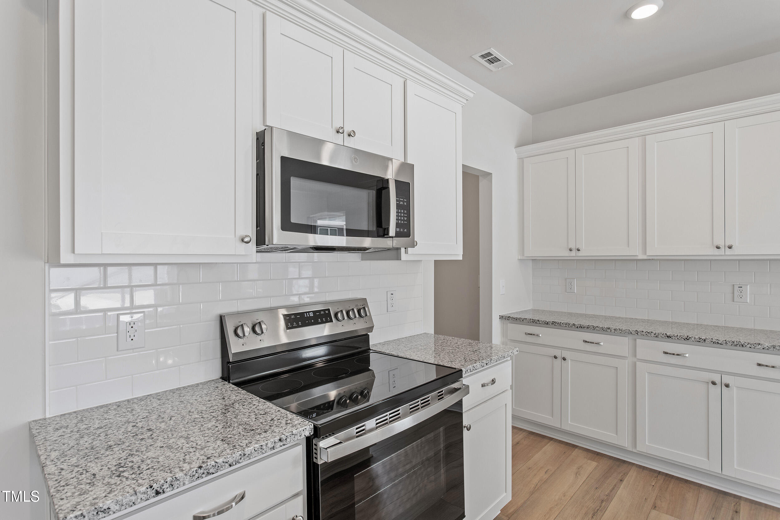 123 Powell Townes Way, Unit 302 Raleigh, NC 27603 - Photo 19 of 44 a kitchen with granite countertop a stove top oven microwave and cabinets