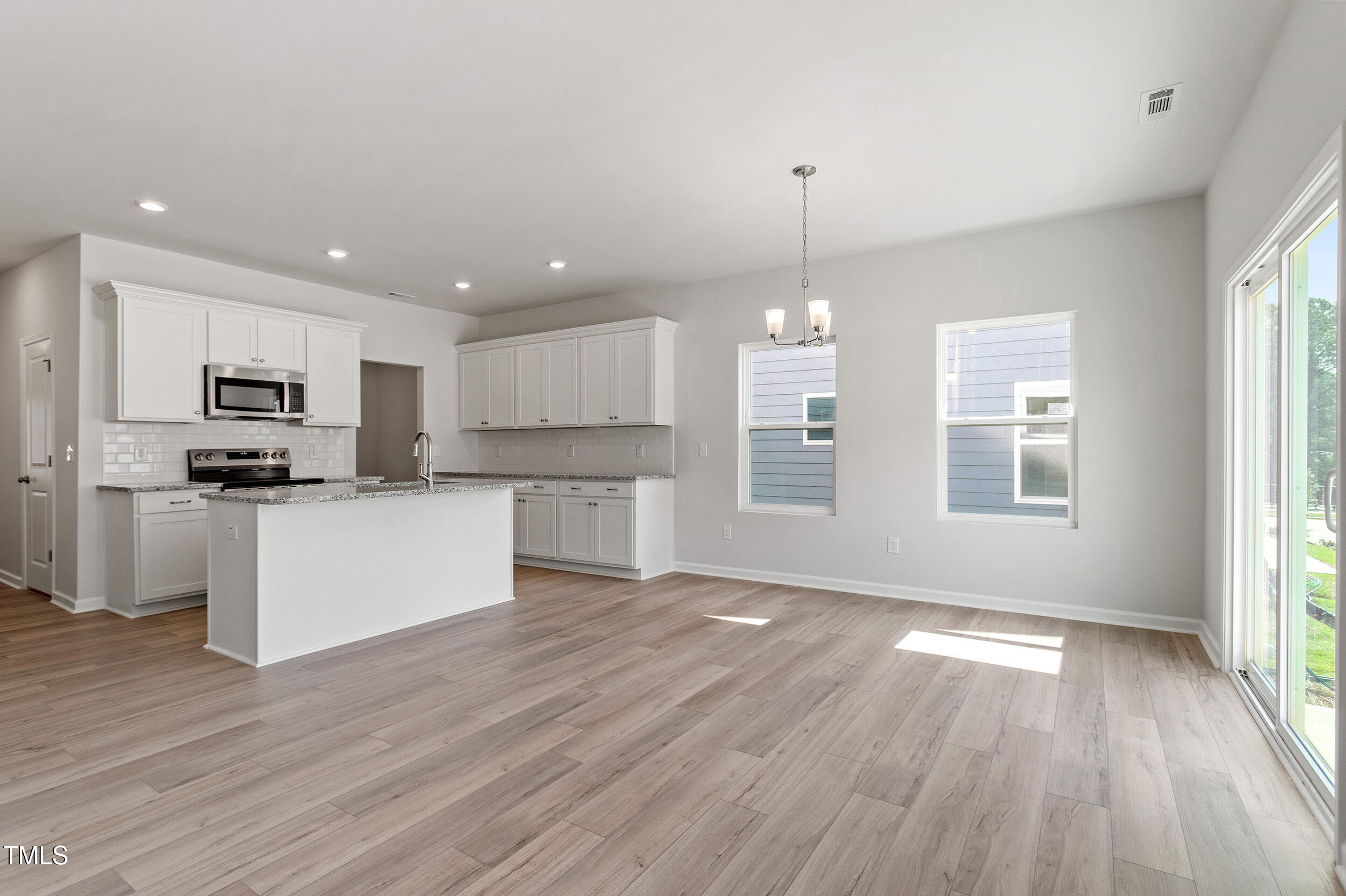 123 Powell Townes Way, Unit 302 Raleigh, NC 27603 - Photo 8 of 44 a view of kitchen with refrigerator microwave and stove with wooden floor