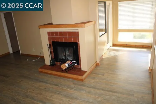 a view of a livingroom with wooden floor and a fireplace