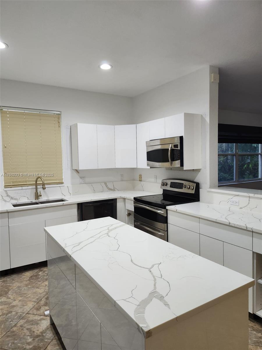 Mission Bay Boca Raton, FL 33498 - Photo 9 of 13 a kitchen with granite countertop a stove top oven a sink a counter space and cabinets