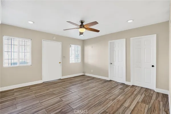 an empty room with wooden floor ceiling fan and windows
