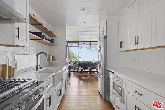 a kitchen with sink a stove and white cabinets with wooden floor