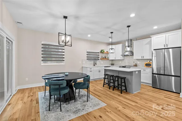 a kitchen with a table chairs a sink dishwasher refrigerator and cabinets