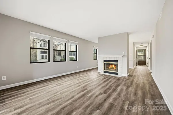 a view of an empty room with wooden floor fireplace and a window