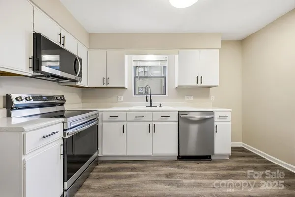 a kitchen with stainless steel appliances granite countertop a sink dishwasher a stove and a microwave oven with cabinets