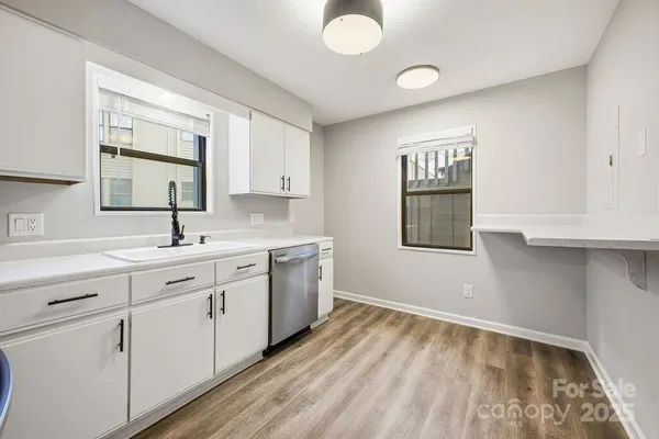 a view of a kitchen with a sink wooden cabinets and a window