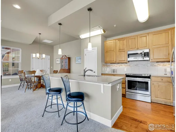 a open kitchen with stainless steel appliances granite countertop a stove a sink a oven a dining table with chairs and cabinets
