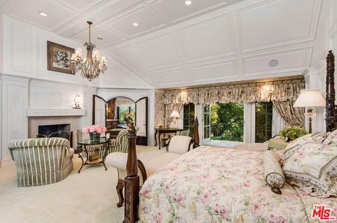 a view of a bedroom with furniture chandelier and a fireplace
