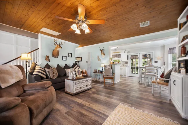 a living room with furniture kitchen view and a wooden floor