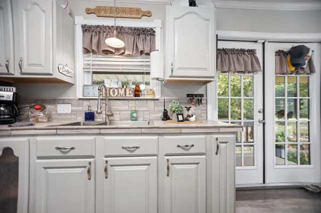 a kitchen with white cabinets and window