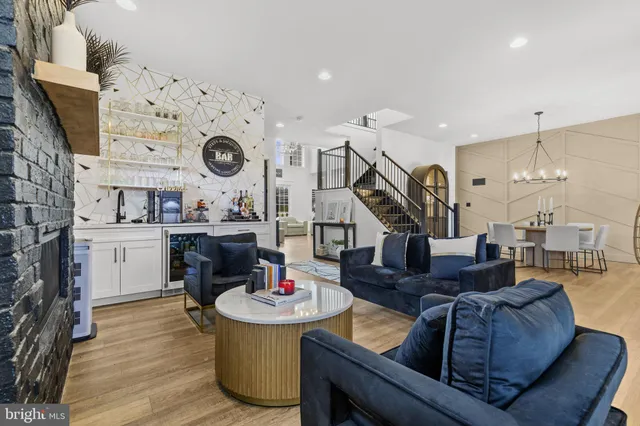 a living room with stainless steel appliances furniture a flat screen tv and kitchen view