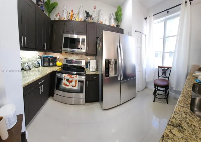 a kitchen with stainless steel appliances granite countertop a stove a sink dishwasher a refrigerator and a microwave oven with a dining table