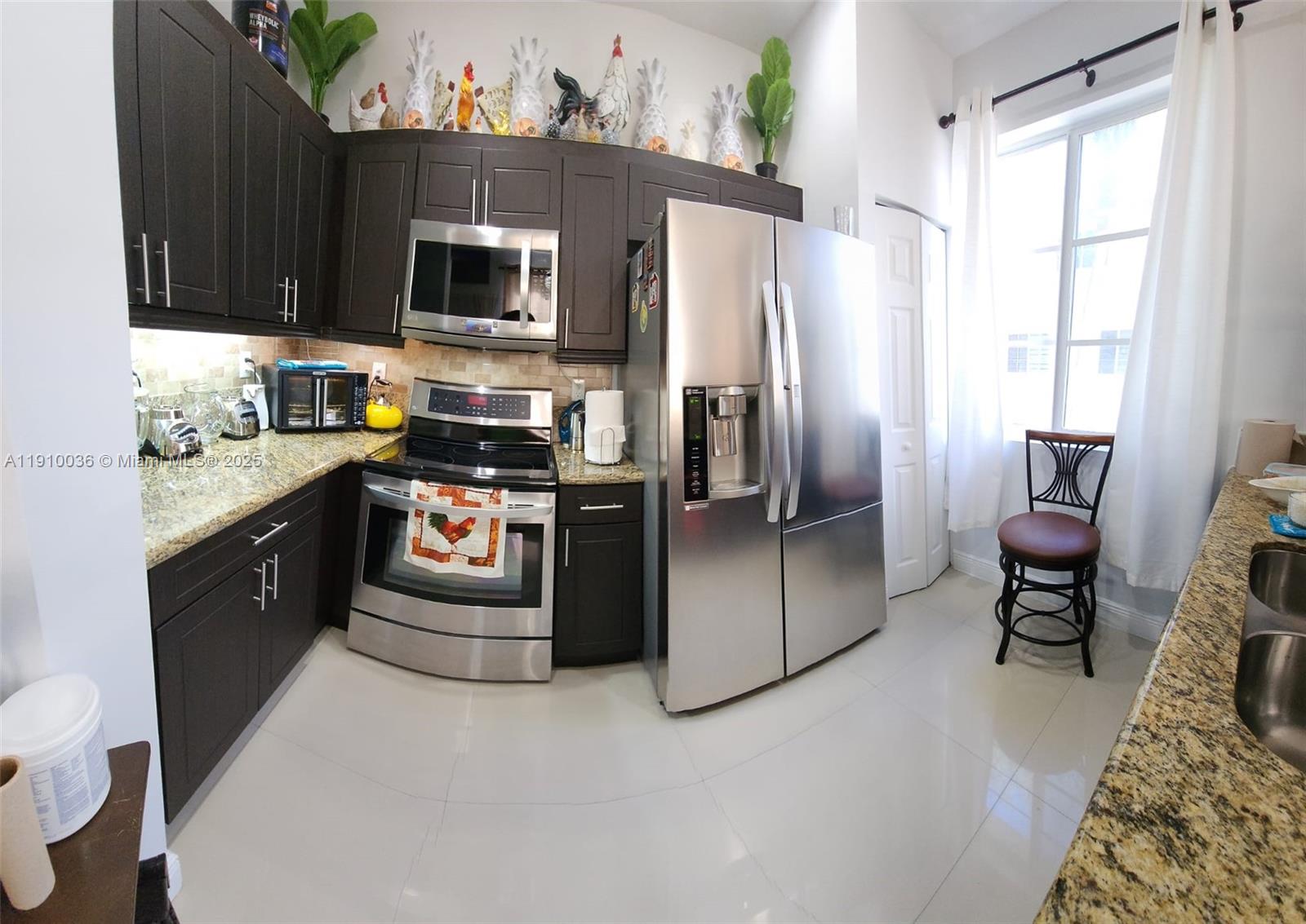 12430 Southwest 50th Street, Unit 147 Miramar, FL 33027 - Photo 4 of 14 a kitchen with stainless steel appliances granite countertop a stove a sink dishwasher a refrigerator and a microwave oven with a dining table