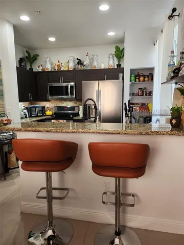 a kitchen with stainless steel appliances a sink a counter top space cabinets and a couch